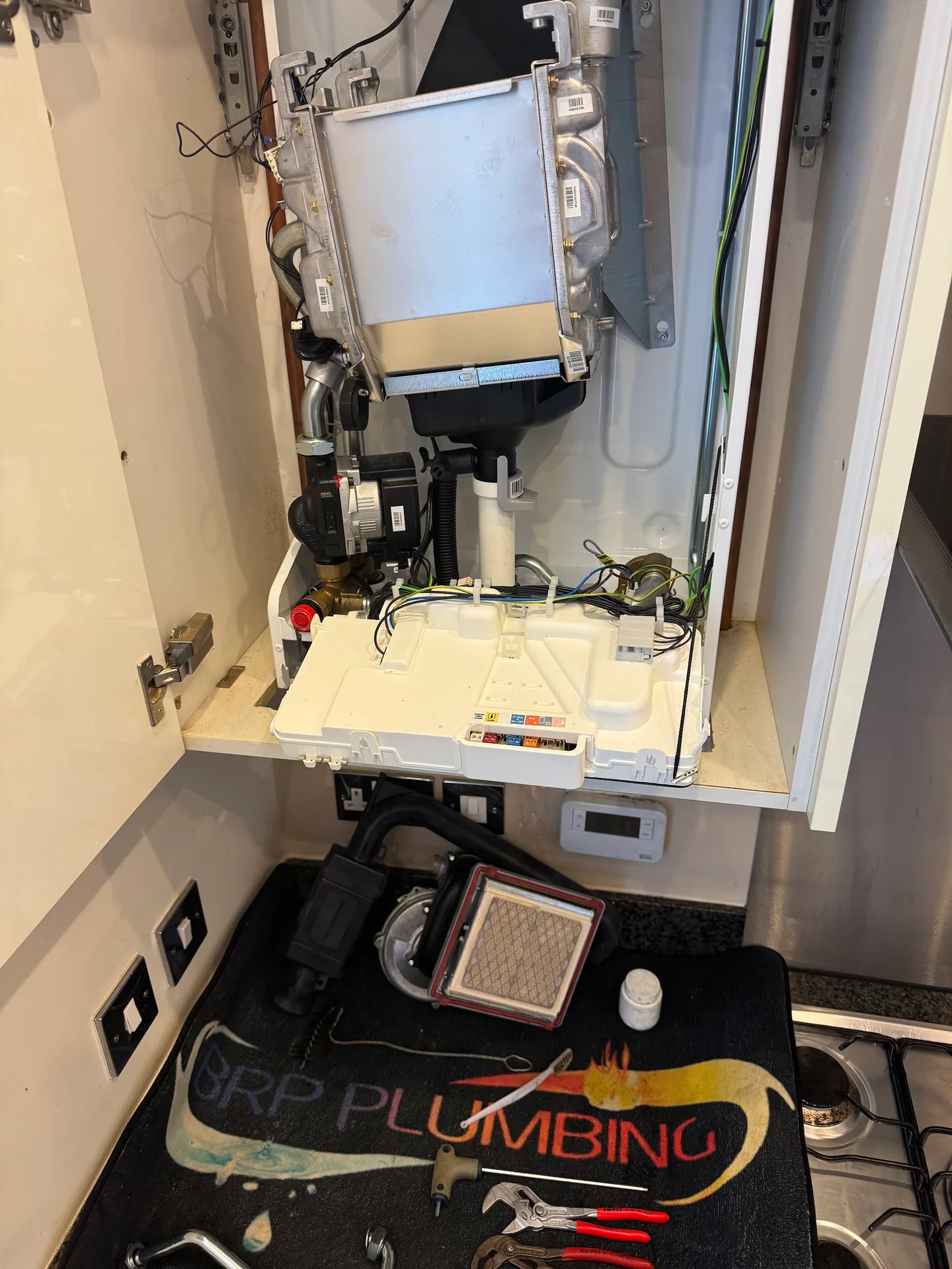 A boiler being serviced with BRP Plumbing tools and branded protective mat