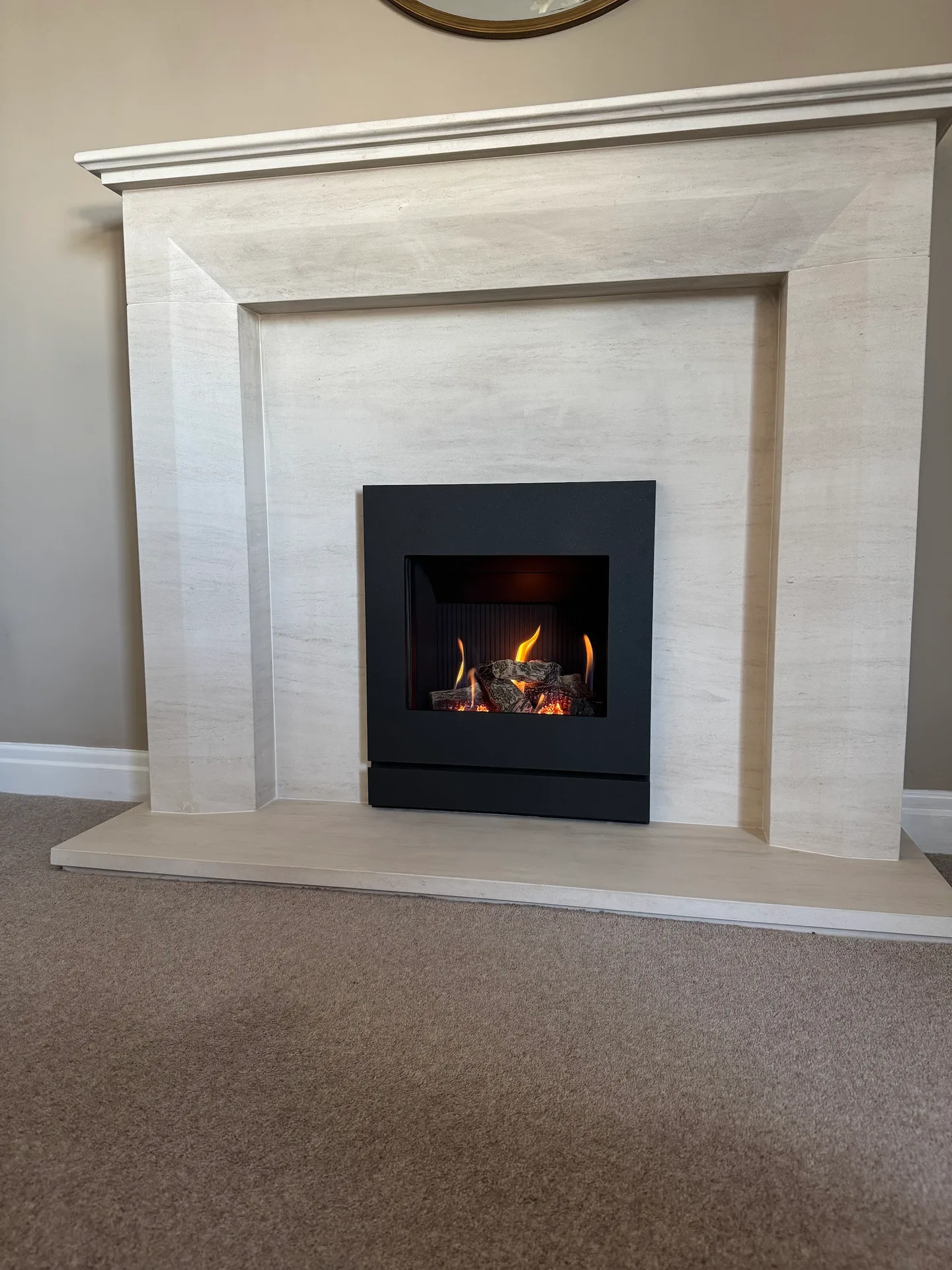 Finished gas fire installation in a pale stone fireplace surround