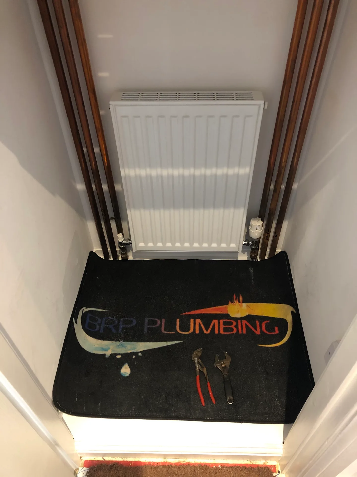 Radiator installation with the BRP Plumbing work mat protecting the floor